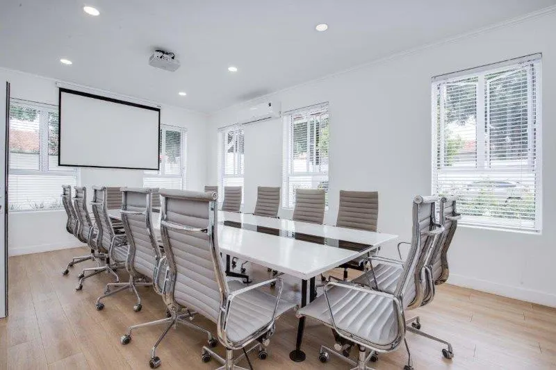 Boardroom with a long white table and projector screen